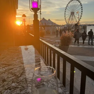 a glass of wine on a table with a ferris wheel in the background