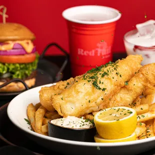 a plate of fish and fries with lemon wedges