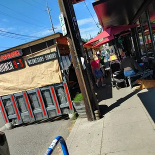 a man walking down the sidewalk in front of a restaurant