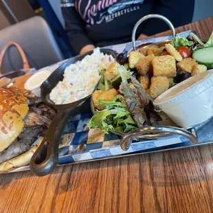 Sliced Brisket Sandwich with potato salad and a salad.
