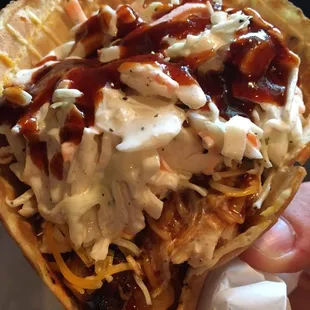 a hand holding a taco covered in shredded cheese and sauce