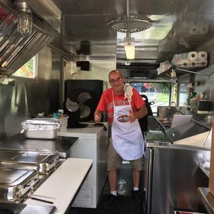 a man in a red shirt standing in the kitchen