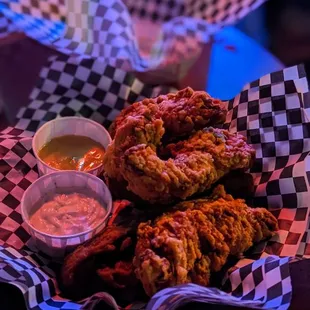 a basket of fried chicken with dipping sauce