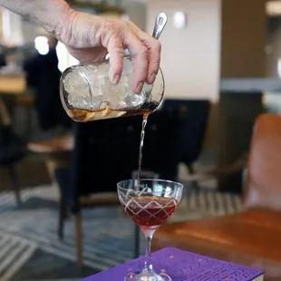 a person pouring a drink into a glass
