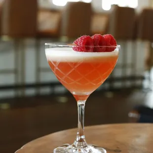a raspberry cocktail in a coupe glass