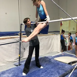 Coach Svetlana spotting kip-up on bars