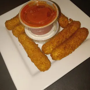 a plate of fried chicken sticks and a bowl of tomato sauce