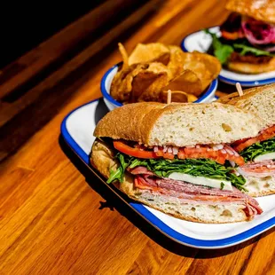 two plates of sandwiches on a wooden table