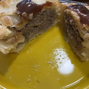 Meat pie, cut open with HP sauce on top.