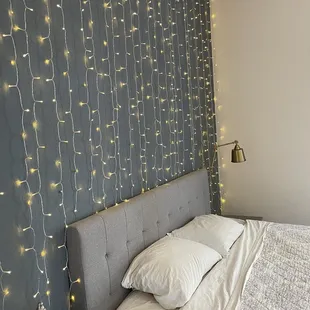 a bed with a headboard and lights on the wall