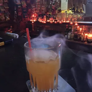 a glass of orange juice on a table with candles in the background
