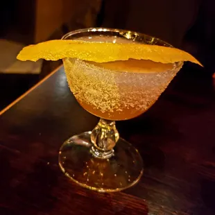 a drink in a glass with an orange garnish