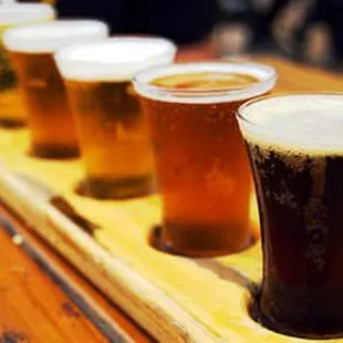 a row of beer glasses on a wooden tray