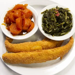 a plate of fish, vegetables, and breadsticks