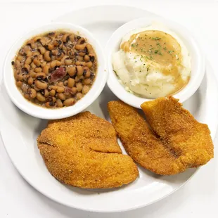 a plate of fried fish, beans, mashed potatoes and mashed potatoes