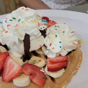 a waffle with whipped cream, strawberries, and bananas