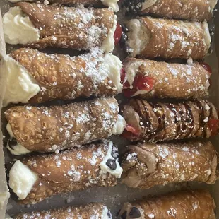 A Dozen cannolis ranging in flavors including strawberry, chocolate, espresso, and traditional
