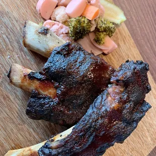 a wooden cutting board with meat and vegetables