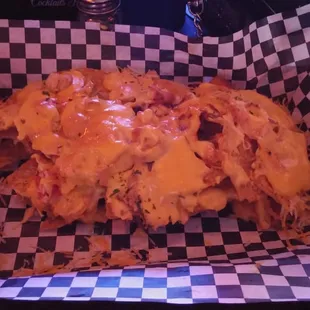 Half eaten Dugout nachos. Topped in chicken, bacon, tomato, shredded cheese, and cheese sauce.... ANAZING