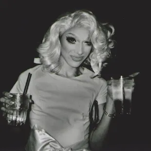 a black and white photo of a woman holding a drink