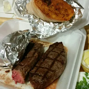 Large 14oz steak cooked medium well, baked potato and bread with butter and sour cream and chilves