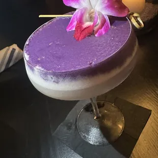 a purple cocktail with a flower on top