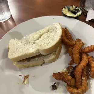a half eaten sandwich and fried onion rings