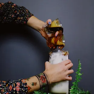a person pouring a drink into a glass