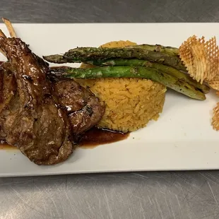 a plate of food with meat, rice and asparagus