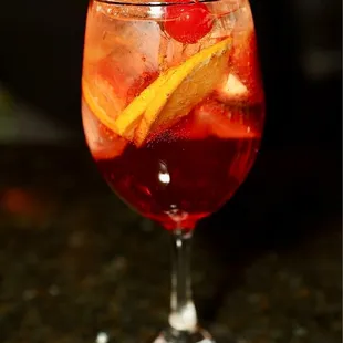a drink in a wine glass with a cherry garnish