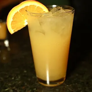 a glass of orange juice with a slice of orange
