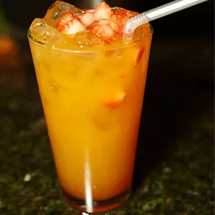 a glass of orange juice with a straw