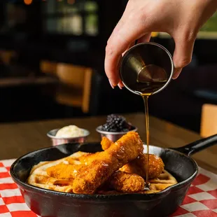 a person pouring syrup over a pan of food