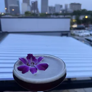 a person holding a drink with purple flowers in it