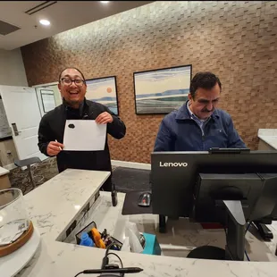 Carlson, the Valet guy holding the note standing next to Asme in a :janitor-like" outfit.