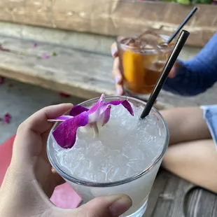 a person holding a drink with a flower in it