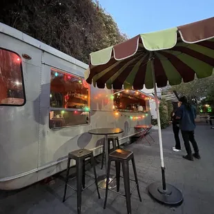 a food truck with tables and chairs under an umbrella