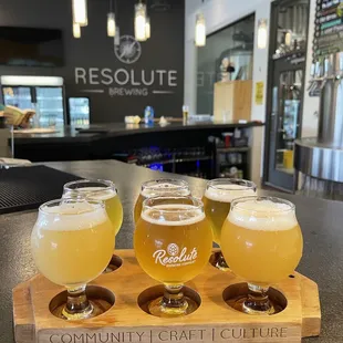 five glasses of beer on a wooden tray