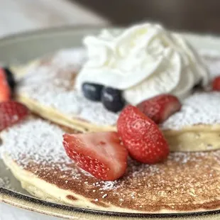 a plate of pancakes with strawberries and blueberries
