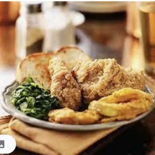 a plate of fried chicken, bread, and greens