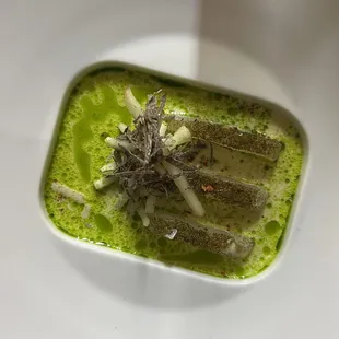 a white plate with a green soup in it