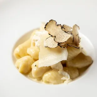 a white plate of pasta with white trufs