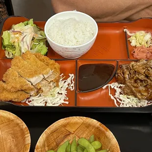 a tray of food with rice, meat, and vegetables