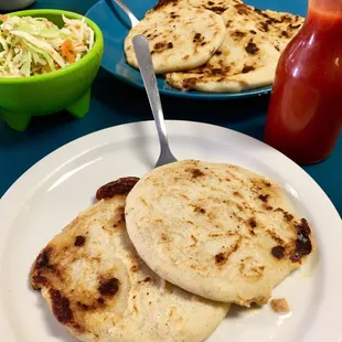 2 mixed pupusas along with the hot sauce and garnishment to put on top.