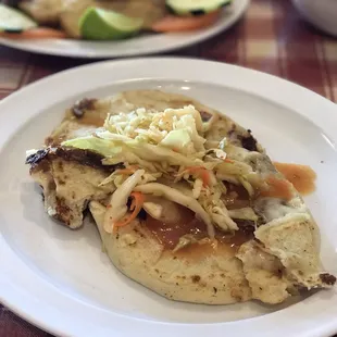 Pupusa revuelta (cheese, bean, shredded pork) with salsa and curtido on top