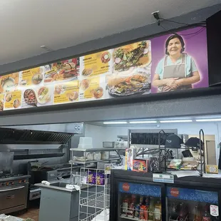 a restaurant counter with a menu on the wall