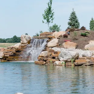 a small waterfall in the middle of a pond