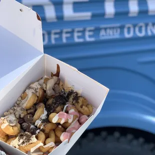 a person holding a box of donuts