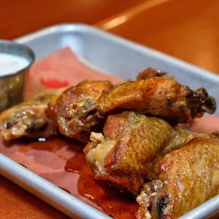 a tray of chicken wings with sauce