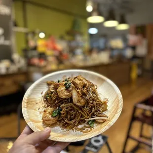 a person holding a plate of noodles